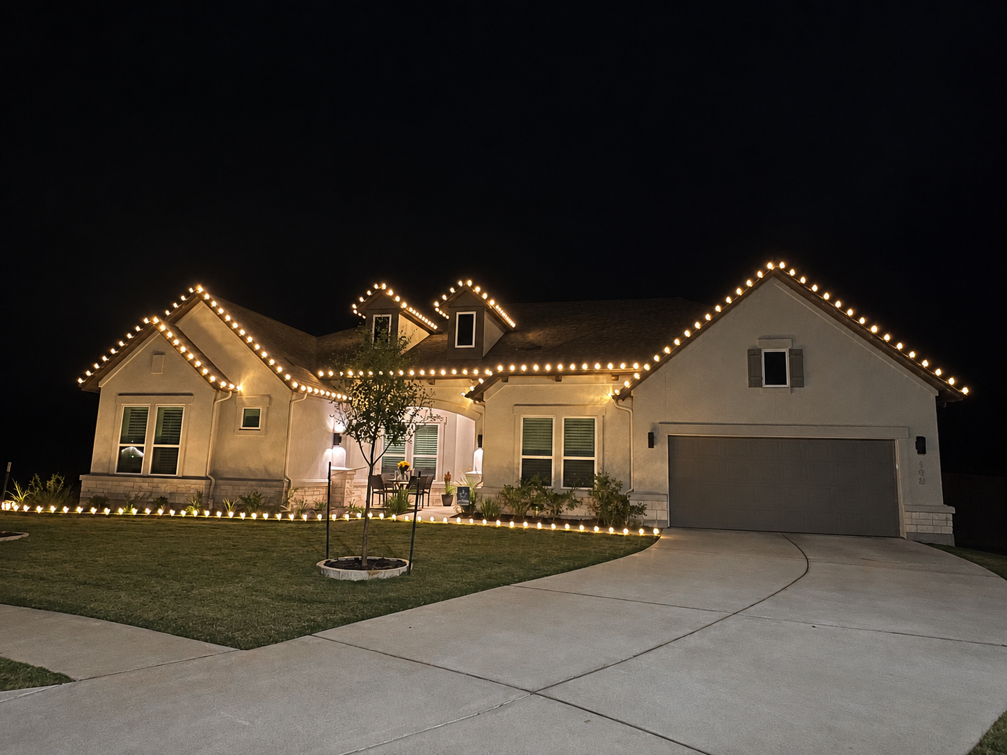 Single-story Bastrop home with warm roofline and lawn lighting